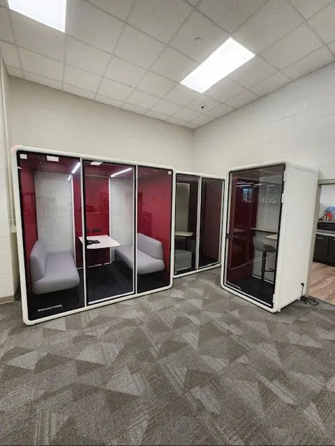 PrivacyPod M Pods with red interiors installed along a library wall
