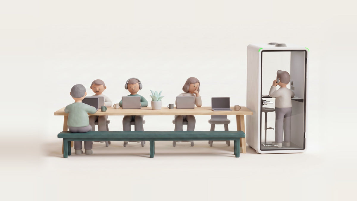 Illustration of a long shared table where four people work on laptops beside one empty seat, while the person who left it takes a phone call at the desk shelf inside a one-person glass booth at the end of the table.