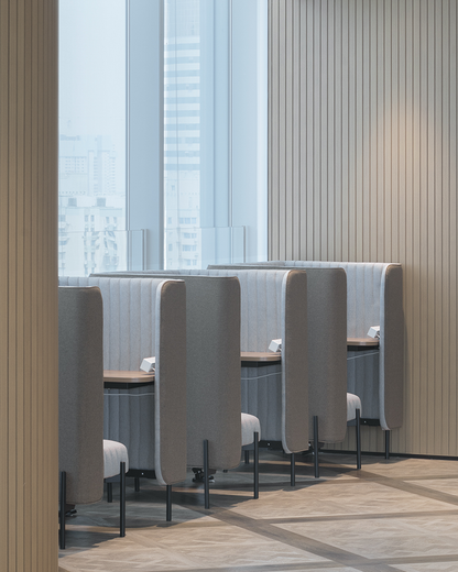 Modern office interior with stylish gray booth seating and large windows in a high-rise building.