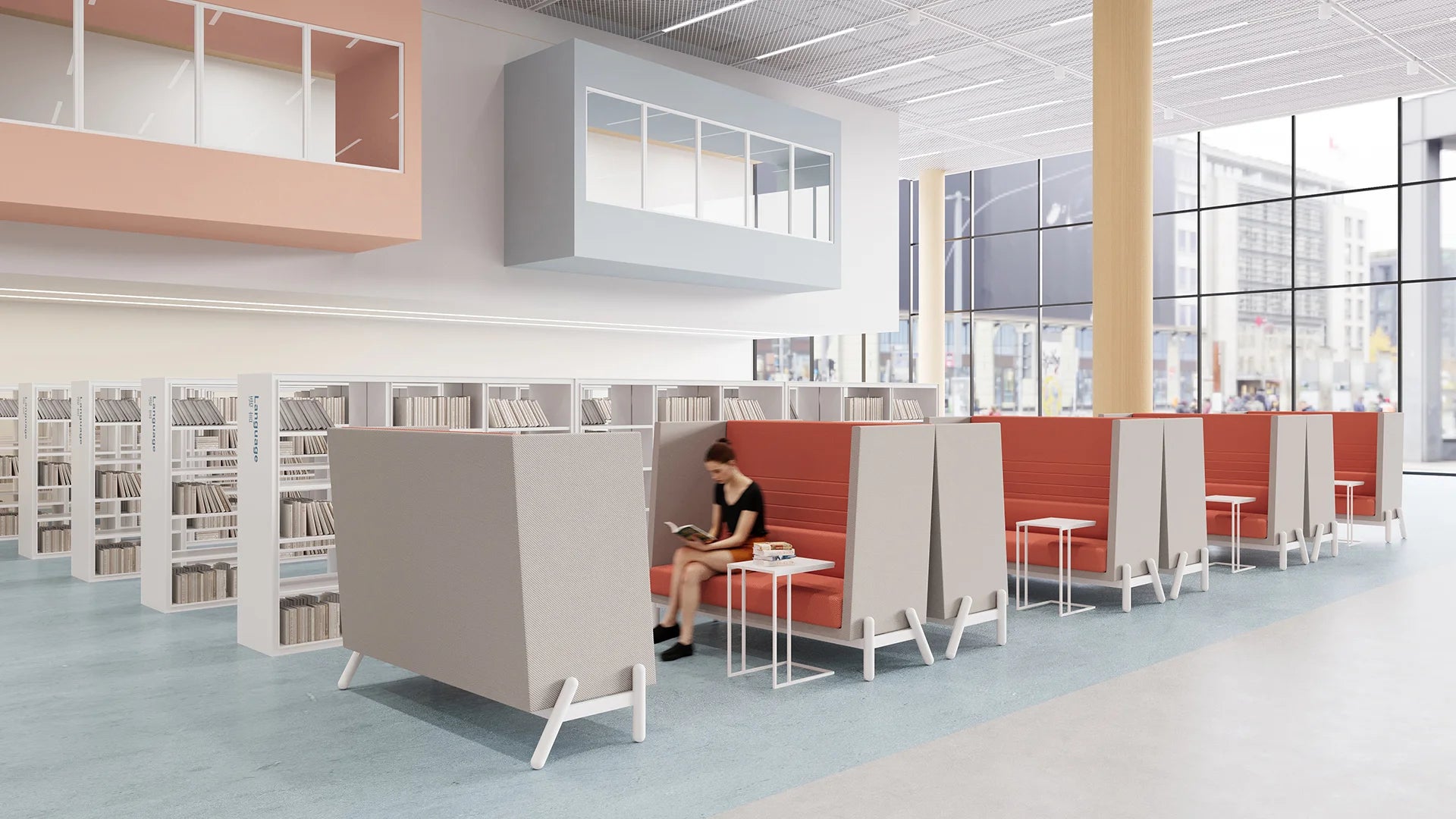 Modern library interior with study booths, bookshelves, and large windows; a person reading in a booth.