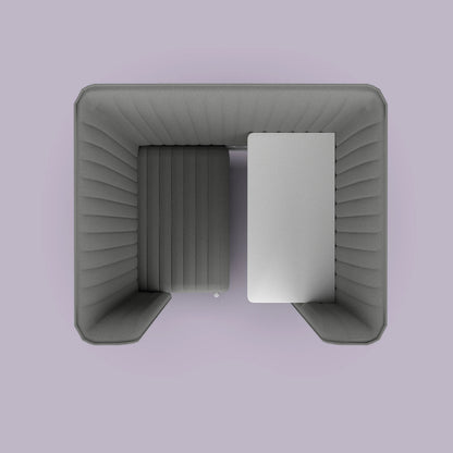 Top view of a modern gray office booth with a cushioned interior and a white desk on a purple background.